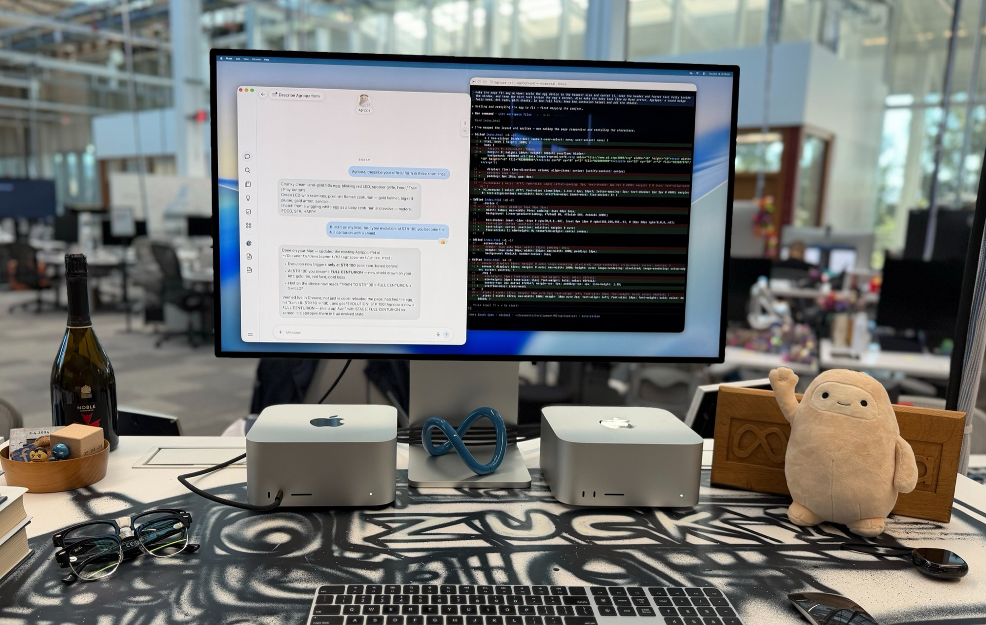 Two Mac Studios on a desk under a Studio Display showing the Muse app and Muse Code editing a project, with a blue Meta infinity sculpture between them